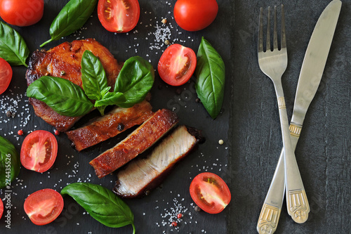 Appetizing meat steak on a stone board with basil and tomatoes. Keto diet. Pegan Diet. Paleo diet.