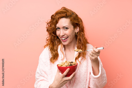 Redhead woman in dressing gown holding a bowl of cereals