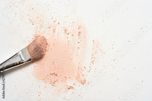 Pink make up spilled over white surface with make up brush covered in powder