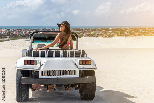 Beautiful happy young woman with buggy ride through the dunes of the coast of Brazil.