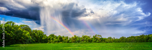 Rain And Rainbow Over Rural Landscape With Trees And Plant Crop