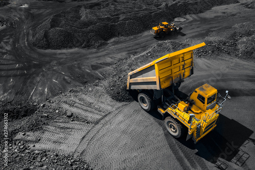 Open pit mine industry, big yellow mining truck for coal, top view aerial drone