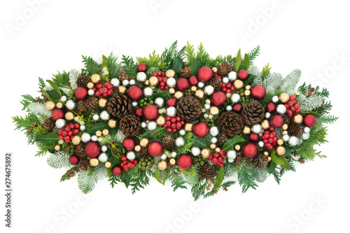 Festive Christmas table decoration with red, silver and gold bauble decorations and winter flora with pine cones on white background with copy space.