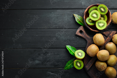 Fresh kiwi and green leaves on the table. Rustic style. Fruits. Top view. Free space for text.