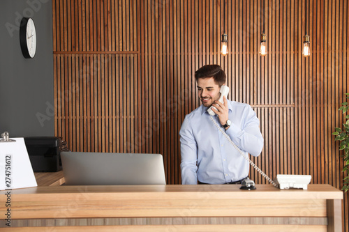 Receptionist talking on phone at desk in lobby