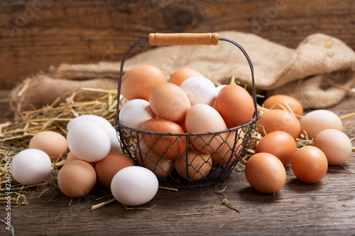 basket of colorful fresh eggs on wooden table