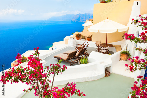 Beautiful terrace with flowers and chaise lounges overlooking the sea. Santorini island, Greece.