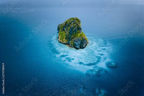 Aerial drone view of a beautiful secluded cliff island surrounded by azure turquoise blue ocean water. Bacuit archipelago is one of the best places for diving. El Nido, Palawan