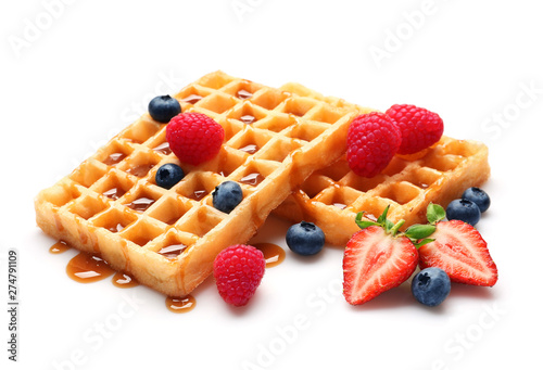 Yummy waffles with berries and caramel syrup on white background