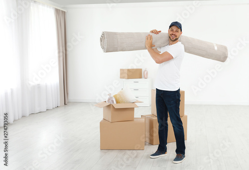 Moving service employees with cardboard boxes and carpet in room