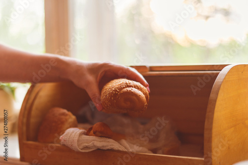 woman taking a bread loaf from a bread box in the kitchen at home