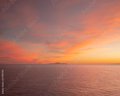 sunset over the sea with an island in the distance