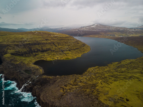 Aerial panorama view of famous Sorvagsvatn Lake / Leitisvatn Lake from above during a moody spring evening with Bosdalafossur waterfall and dark blue sea (Faroe Islands, Denmark, Europe)