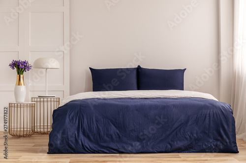 Simple navy blue and white bedroom interior with cozy bed with pillows and duvet