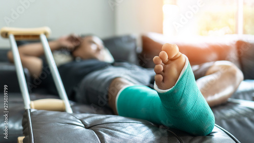 Bone fracture foot and leg on male patient with splint cast and crutches during surgery rehabilitation and orthopaedic recovery staying at home