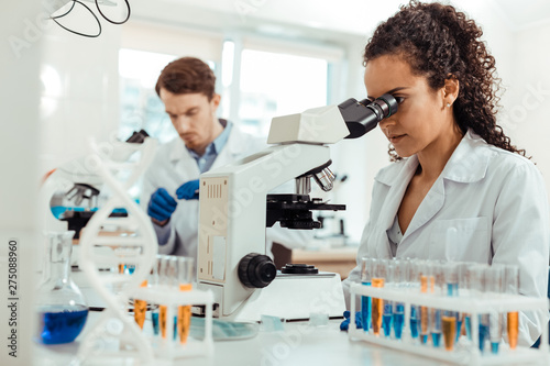 Smart female biologist looking into the microscope