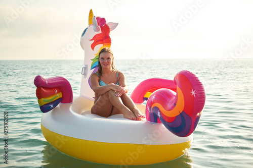 Lifestyle portrait of young beautiful girl with inflatable pool unicorn at sunset