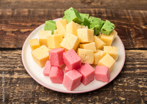 Cheese cubes of green, yellow and red color on the plate, appetizer for wine. Close up