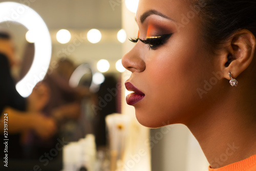 Close-up portrait young woman African American with perfect skin and radiant make-up in orange-coloured shades. Sensitive profile. Beauty industry. Space for text.