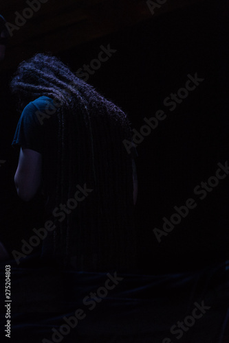 Hombre rasta espaldas en fondo negro orando cantando camisa azul oscura