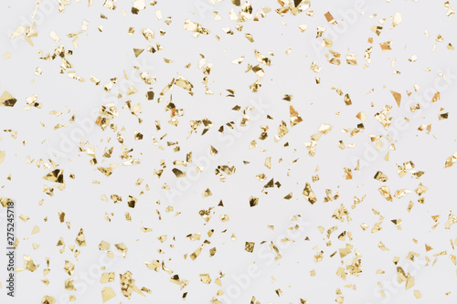 Golden confetti on white background. Festive, party or holiday glitter backdrop. Flat-lay, top view.