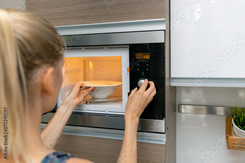 woman warm up the food in microwave oven at home