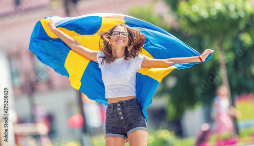 Happy girl tourist walking in the street with sweden flag