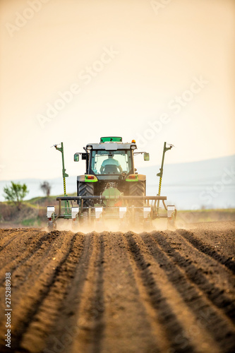 Farmer seeding, sowing crops at field. Sowing is the process of planting seeds in the ground as part of the early spring time agricultural activities.