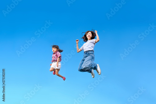 青空を背景に一緒にジャンプする親子。 絆、愛情、幸せ、飛躍、未来イメージ