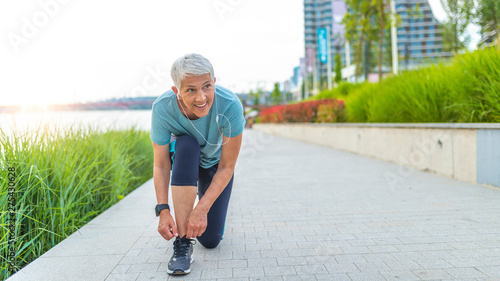 Female runner tying her shoes preparing for a run a jog outside. Close up of young woman tying her laces before a run. A fit and active woman tying her shoes before jogging in a park.