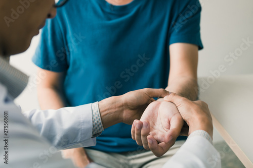 Physical therapist checks the patient wrist by pressing the wrist bone in clinic room.