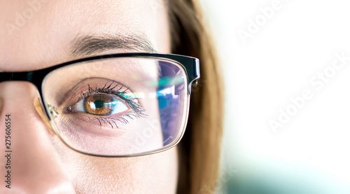 Close up of eye and woman wearing glasses. Optometry, myopia or laser surgery concept. Brown eyed girl with spectacles and eyeglasses. Macro portrait of face and specs. Light reflection on lens.