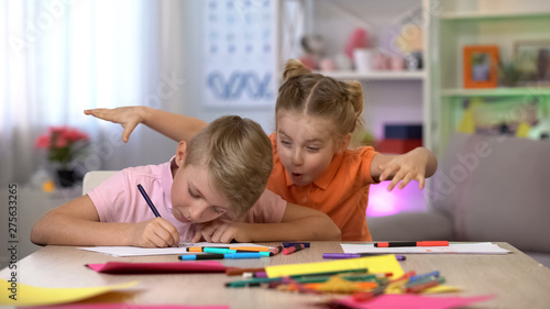 Girl scaring brother studying at table, child hyperactivity, attention deficit