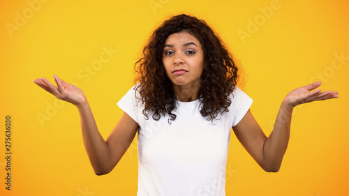 Afro-american female showing no idea gesture, unsure of choice, hesitation