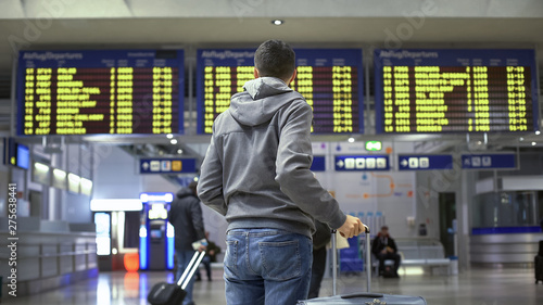 Man traveler looking at time table in train station, preparing for departure