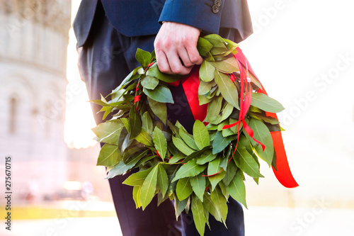 Giovane laureato con corona d'alloro verde e nastro rosso tenuto in mano. Cerimonia di laurea.