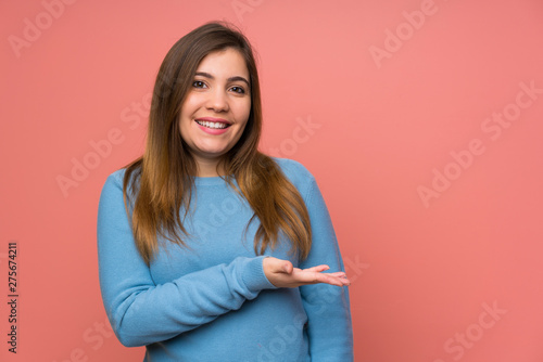 Young girl with blue sweater extending hands to the side for inviting to come