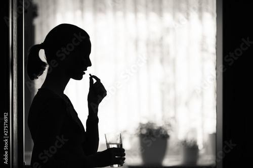 Female taking pill medication in a home setting. 