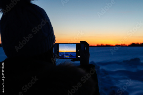 girl photographs sunset in winter