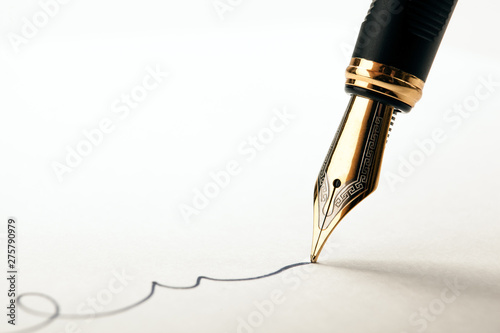 golden fountain pen leaves a signature on a white paper