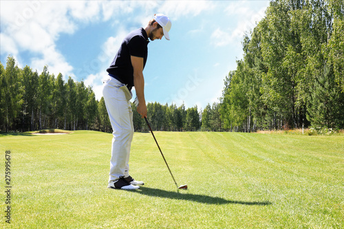 Full length of golf player playing golf on sunny day. Professional male golfer taking shot on golf course.