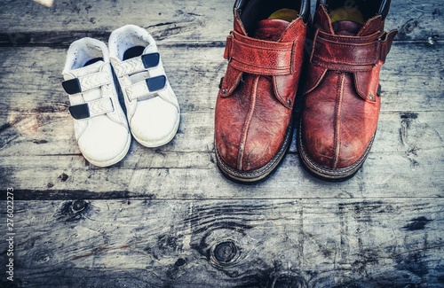 Father boots and baby shoes on wooden background, fathers day. Daddy's boots and baby's shoes, fathers day concept.