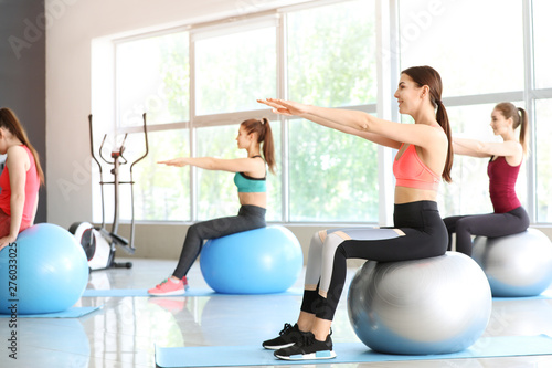 Young sporty women doing exercises with fitballs in gym