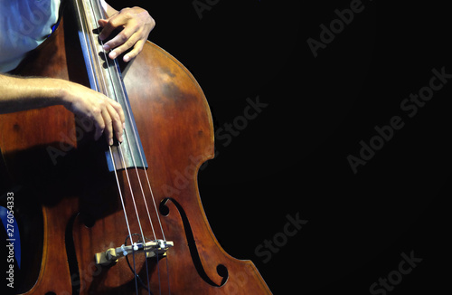 Double bass. The musician playing contrabass musical instrument on black background.