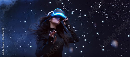 Beautiful woman with flowing hair in futuristic dress over dark background. Girl in glasses of virtual reality. Augmented reality, game, future technology concept. VR.