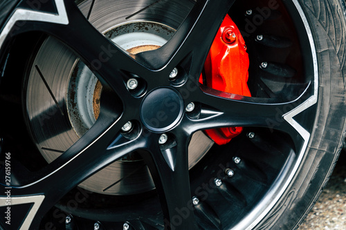 Red brake pads and discs of modern car with black alloy discs.