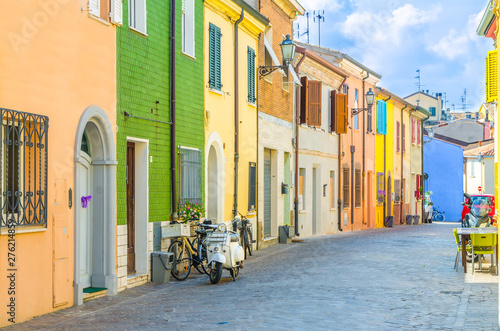 Typical italian old buildings with colorful multicolored walls and traditional houses and motorcycle bike scooter parked on cobblestone street in historical city centre Rimini, Emilia-Romagna, Italy