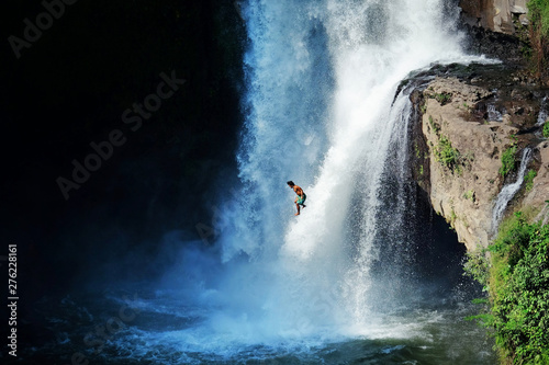 Jumping into the water. Man having fun at waterfalls in the nature. Bali, Indonesia