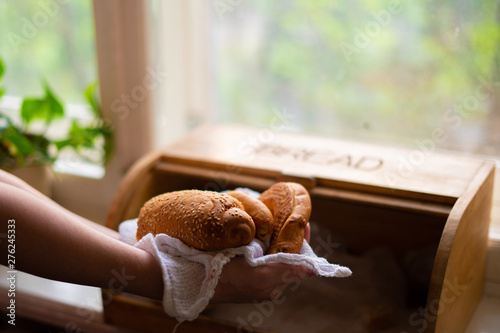 woman taking a bread loaf from a bread box in the kitchen at home