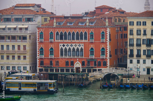 Venetian palace at shore of Canal Grande with water taxi station and clock tower in background